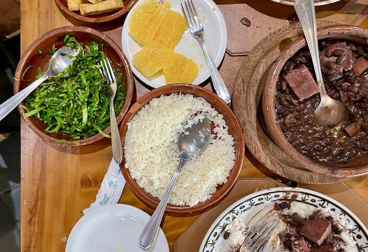 sauteed kale with bacon and garlic couve a mineira, Table with feijoada orange slices kale yuka rice and other plates from Bolinha restaurant in Sao Paulo Brazil