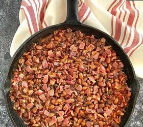 smoked baked beans with bacon and brown sugar, A cast iron skillet filled with smoked baked beans with bacon and brown sugar with a cloth napkin near the handle