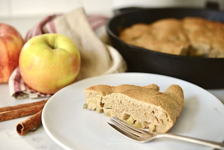 easy spiced sourdough apple oat cake recipe , sourdough apple cake on plate with apples and cast iron skillet