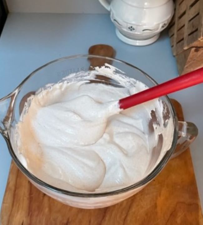 glass mixing bowl of whipped cream and cheesecake mixture