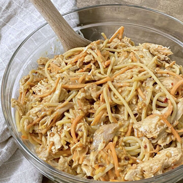 asian inspired chicken and noodles with peanut sauce, Chicken and noodles with peanut sauce being stirred in a glass bowl