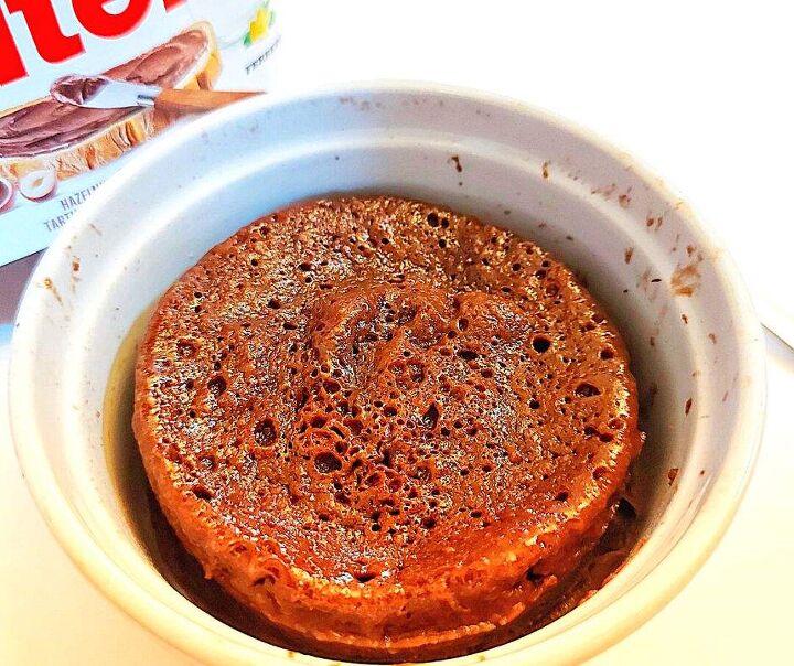 nutella mug cake get your chocolate fix with this easy treat, Nutella mug cake with a jar of Nutella chocolate hazelnut spread in the background