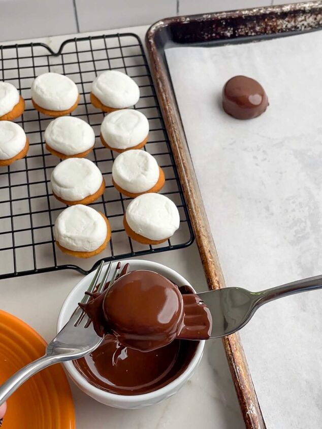 chocolate marshmallow cookies, hands dipping a marshmallow cookie in melted chocolate