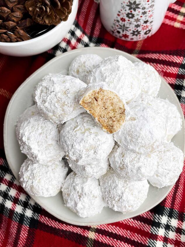 mexican wedding cookies, Mexican Christmas cookies on a white plate next to a holiday mug and bowl of pine cones