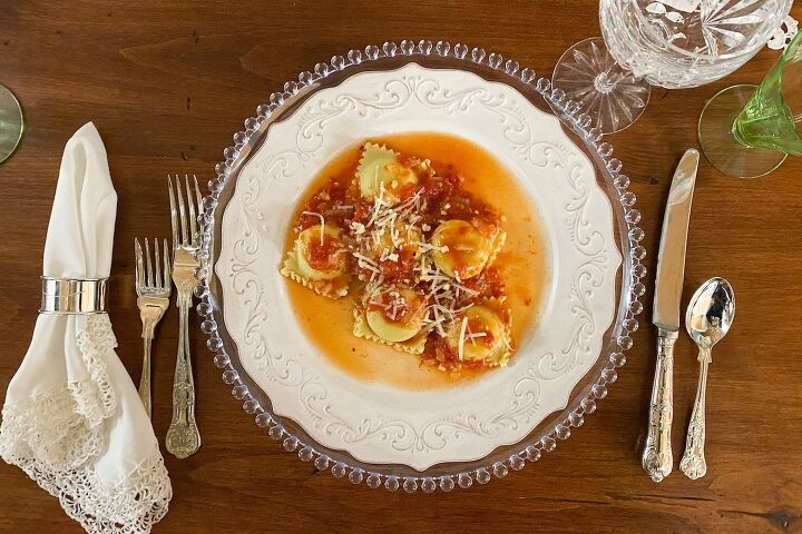 cheesy manicotti with italian sausage tomato sauce, Cheesy Lobster Ravioli with Tomato Sauce on White plate with silverware set on a dark wood table