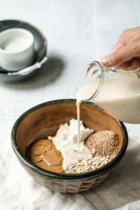 peanut butter overnight oats, overnight oats ingredients in bowl with milk pouring over ingredients