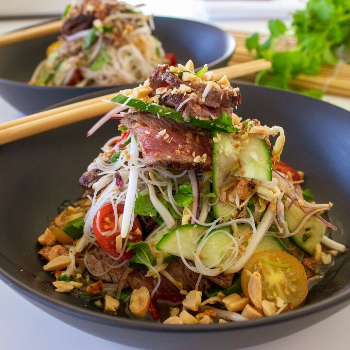 thai beef salad recipe, Two Thai beef salads plated in black bowls