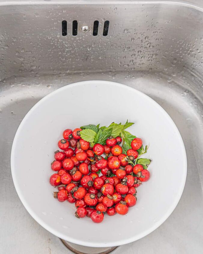 three ways to make dried wild rose hip tea, bowl of unwashed rose hips with a sprig of wild mint