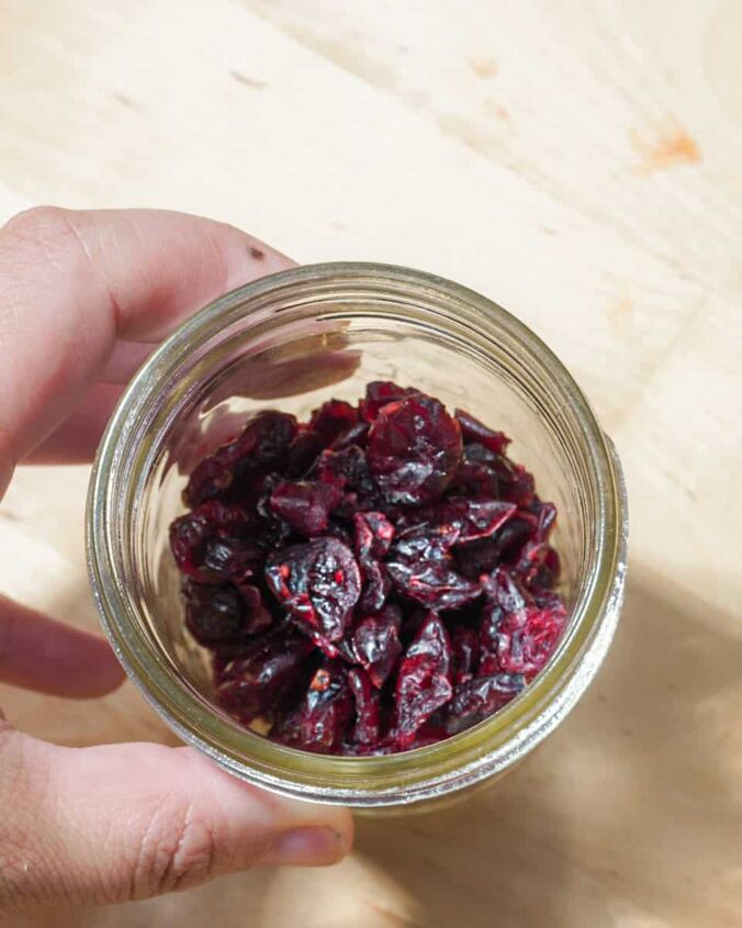 how to dehydrate cranberries, person holding glass jar with dehydrated cranberries
