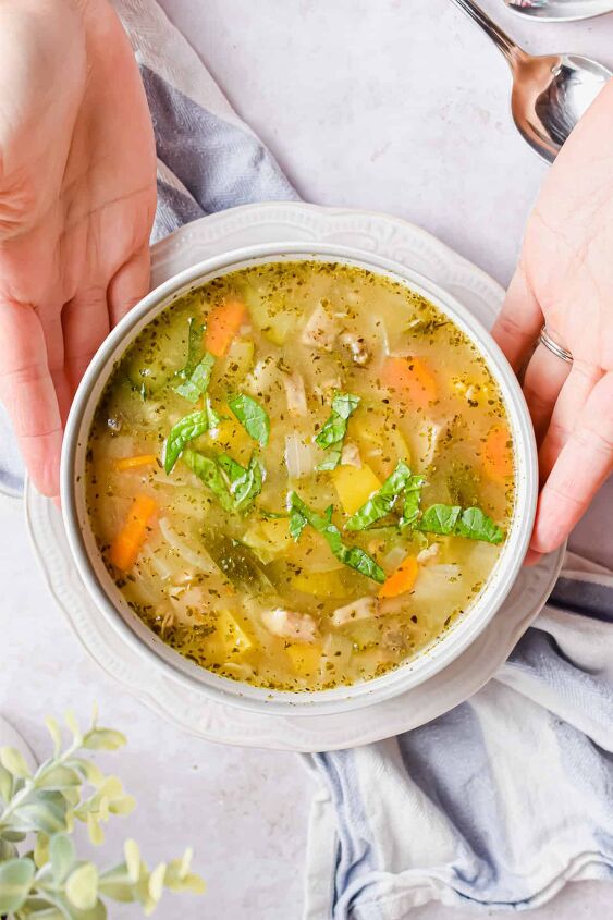 simple instant pot vegetable barley soup, Two hands are holding the bowl of soup