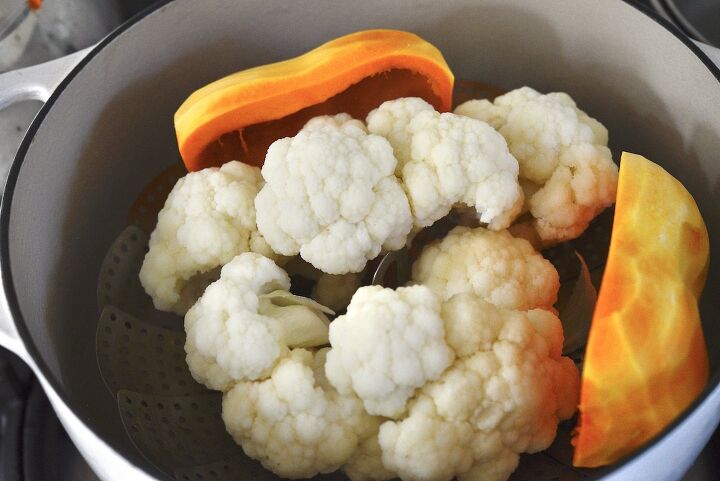 easy cheesy cauliflower pumpkin casserole, cauliflower and pumpkin in steamer basket in large pot