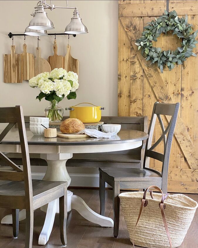 creamy cauliflower soup with basil olive oil, Breakfast nook with a centerpiece on the table including white flowers in a vase a yellow Dutch oven and fresh baked bread with soup bowls
