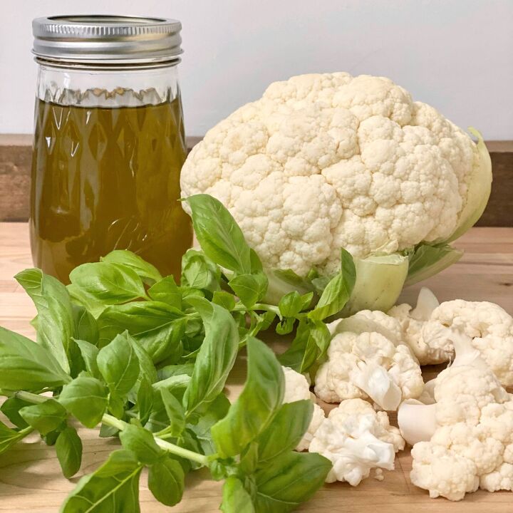 creamy cauliflower soup with basil olive oil, Fresh basil basil olive oil in a mason jar and cauliflower on a cutting board