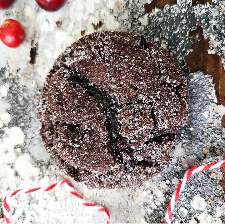 chocolate molasses crinkle cookies, functional image chocolate molasses cookie sprinkled with sugar top down image of cookie closeup on a distressed gray white wood surface styled with red cranberries and red and white holiday twine