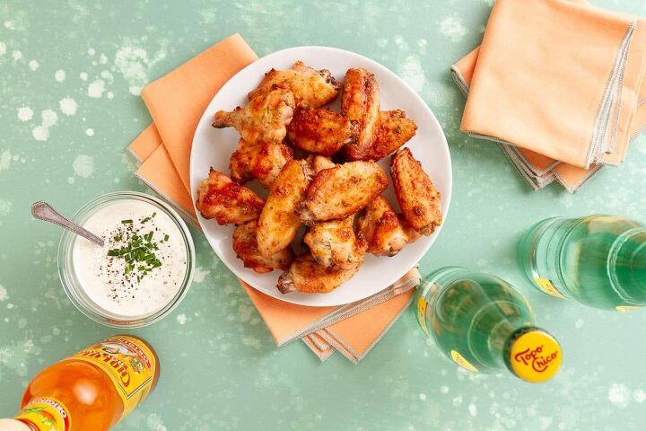 dry rub ranch chicken wings baked, white plate holding baked chicken wings next to white dipping sauce orange napkins and glass bottles