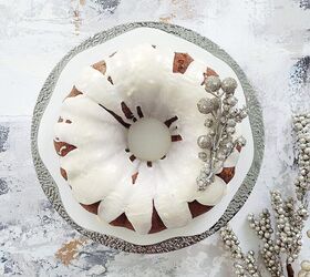 eggnog bundt cake, functional image eggnog cake top down on a silver rimmed cake stand cake is topped with a white eggnog drip glaze and decorated with silver baubles for christmas