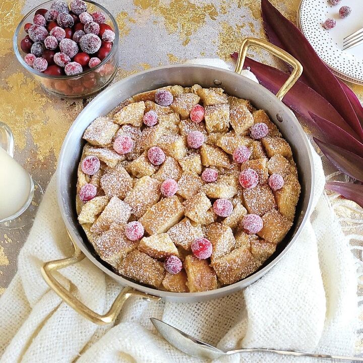 eggnog bundt cake, functional image eggnog bread pudding garnished with fresh cranberries top down photo bread pudding is in a round silver baking pan with gold handles there is a bowl of sugared cranberries and gold polka dot plates