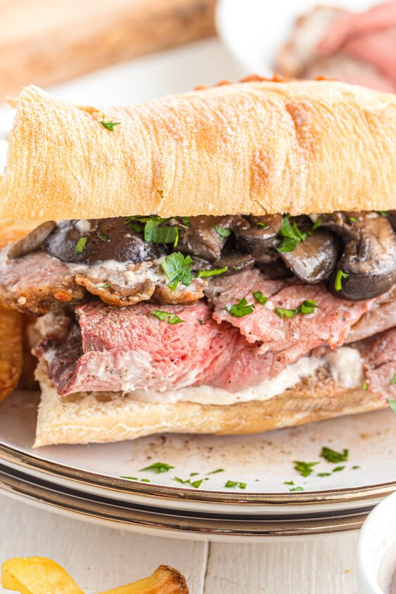 prime rib sandwich, close up of roast beef sandwich with mushrooms and parsley
