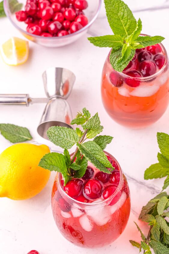cranberry gin cocktail, Two cranberry cocktails on table with lemon and mint