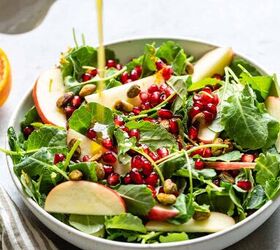 kale and apple salad with maple mustard dressing, dressing being poured onto a kale salad