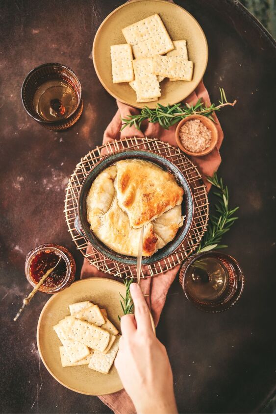 easy baked brie with fig jam and rosemary, Baked brie with a hand reaching in for a scoop