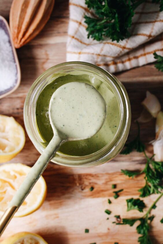 lemon herb tahini sauce, Lemon herb tahini sauce on a spoon resting over a jar