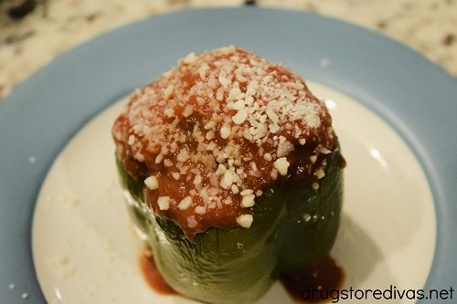 A stuffed green pepper topped with cheese and sauce
