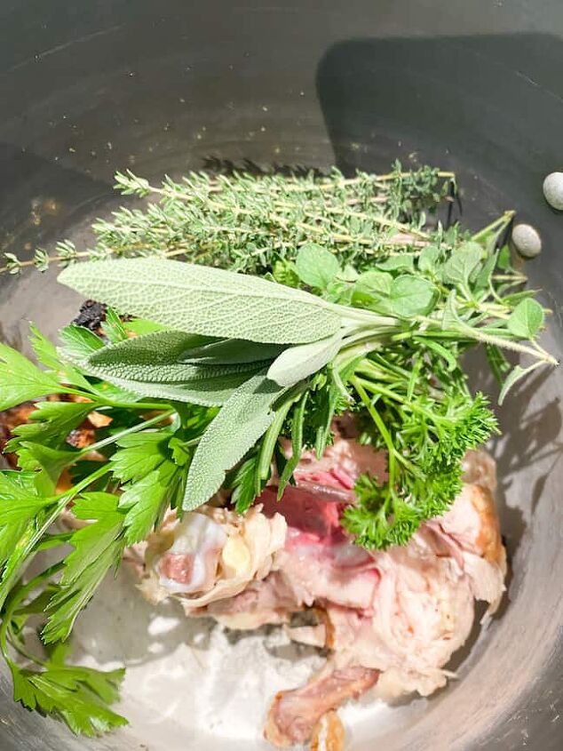classic chicken noodle soup with a twist, pot with chicken bones and fresh herbs to make chicken stock for chicken noodle soup