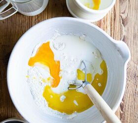 savory buttermilk cheddar belgian waffles, wet waffle ingredients added to dry ingredients in a white mixing bowl