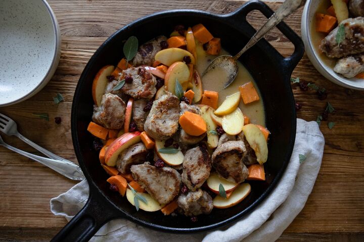 healthy pork tenderloin recipe, black cast iron skillet with pork tenderloin apples and sweet potatoes on a wooden board