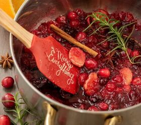 holiday cranberry bourbon cider, A silver sauce pan with gold handles filled with fresh cranberry syrup with whole cinnamon sticks star anise rosemary sprig and ginger pieces