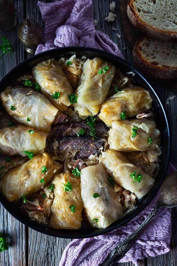 classic bosnian stuffed cabbage rolls sarma, An overhead photo of cabbage rolls placed in a circle in a round dish with smoked meat in the middle