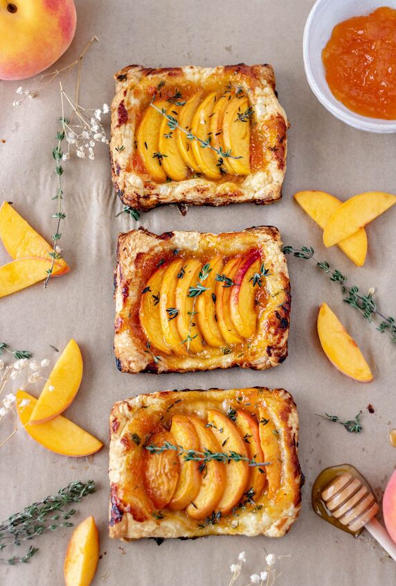 easy peach apricot tarts dairy free, Three mini peach tarts in a row on parchment paper surrounded by peach slices fresh thyme apricot preserves and honey