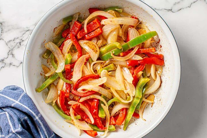 easy steak fajita tacos, onions and bell peppers saute in a white skillet