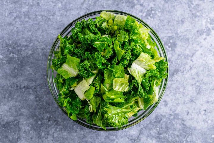 healthy lemon kale caesar salad with chicken, kale and romaine lettuce chunks mixed with the dressing in a bowl