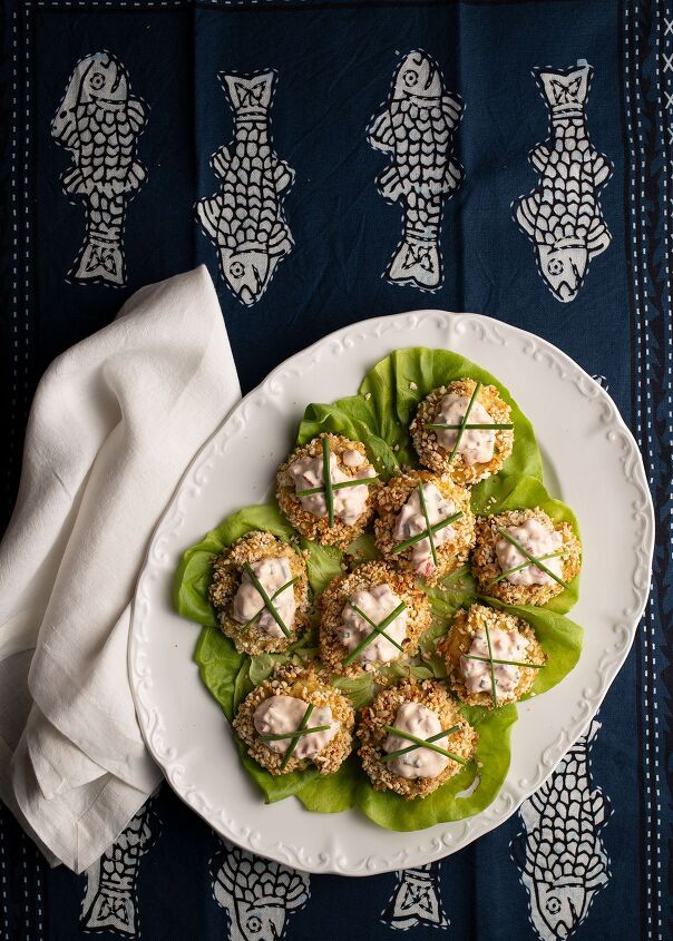 Crabcakes on a lettuce lined white platter with a white linen napkin beside all on a navy blue cloth