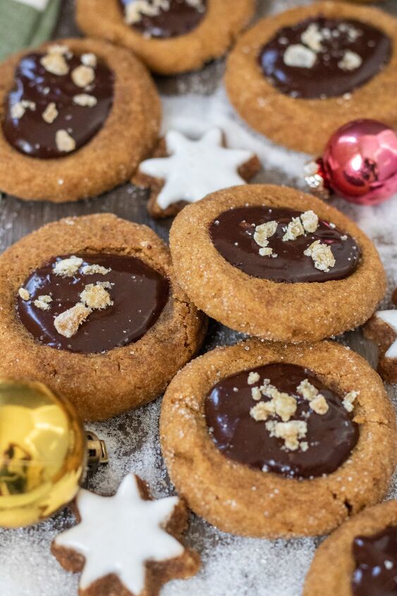 gingerbread mocha thumbprint cookies, Gingerbread thumbprint cookies that are filled with chocolate ganache and topped with candied ginger pieces There s a small gold ornament and sugar in the background that looks like snow