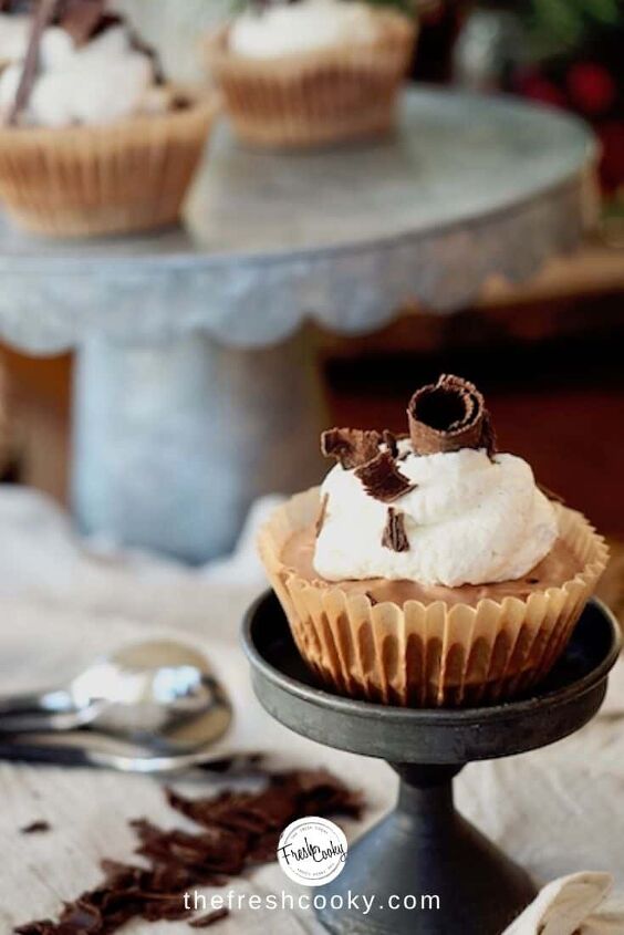 mini chocolate french silk pies in a cupcake wrapper on a metallic stand with a dollop of whipped cream and chocolate shavings thefreshcooky com
