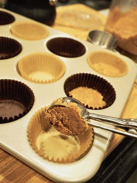 scooping crust mixture into cupcake tin for Mini Chocolate French Silk Pies