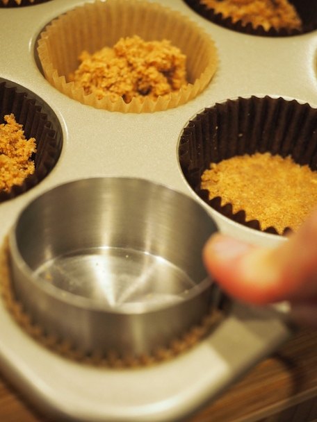 Pressing crust mixture in cupcake tin for Chocolate French Silk Mini Pies