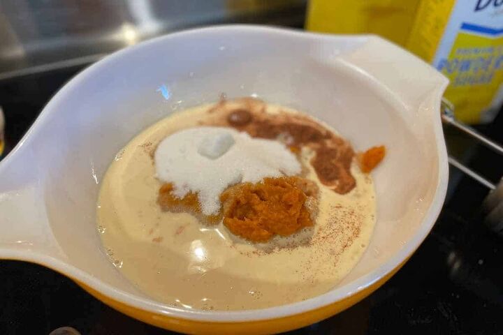 pumpkin crunch cake with yellow cake mix, white mixing bowl with the ingredients for the bottom layer of pumpkin crunch including canned pumpkin sugar cinnamon and evaporated milk