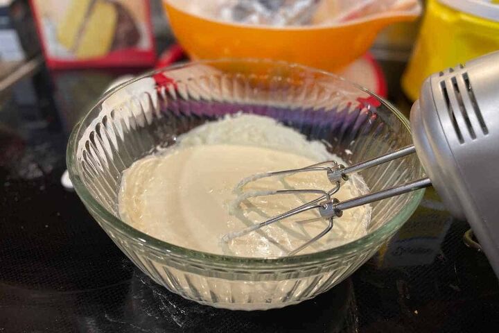 pumpkin crunch cake with yellow cake mix, cream cheese and heavy whipping cream in a bowl with an electric mixer
