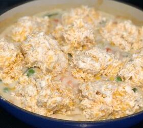 creamy cheddar chicken and biscuits casserole recipe, spoonful of cheddar biscuit dough on top of a pot pie type filling