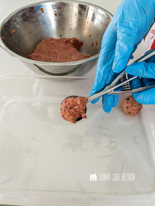 Gloved hand scoops raw meatball mixture to place in a glass pan