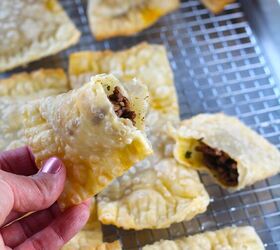brazilian pastel recipe with beef filling, Hand holding half of golden brown fried Pastel over sheet pan of more pasteis for traditional Brazilian Pastel Recipe with ground beef filling