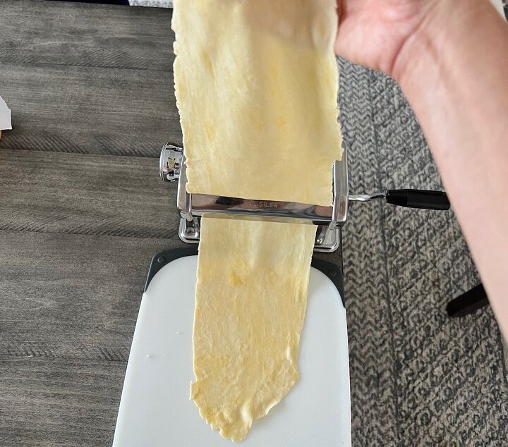brazilian pastel recipe with beef filling, Hand holding thin dough sheet as it goes through the thinnest setting of the pasta rolling machine for Brazilian Pastel recipe