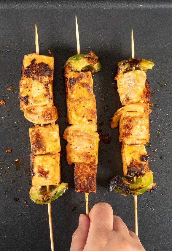 tofu skewers vegan shish tawook sandwich, three skewers with tofu cubes and vegetables on a grill