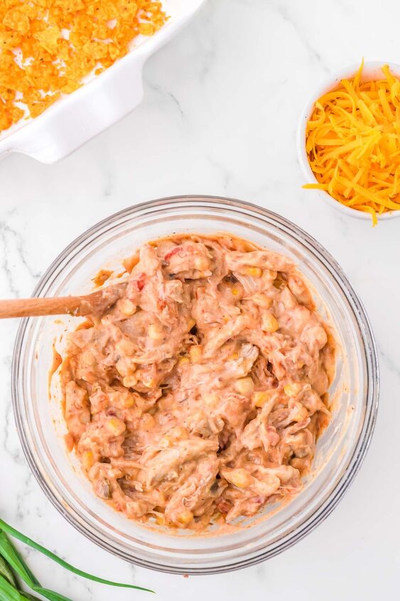 mexican chicken casserole with doritos, Chicken chicken soup corn and spices being stirred together in a glass bowl