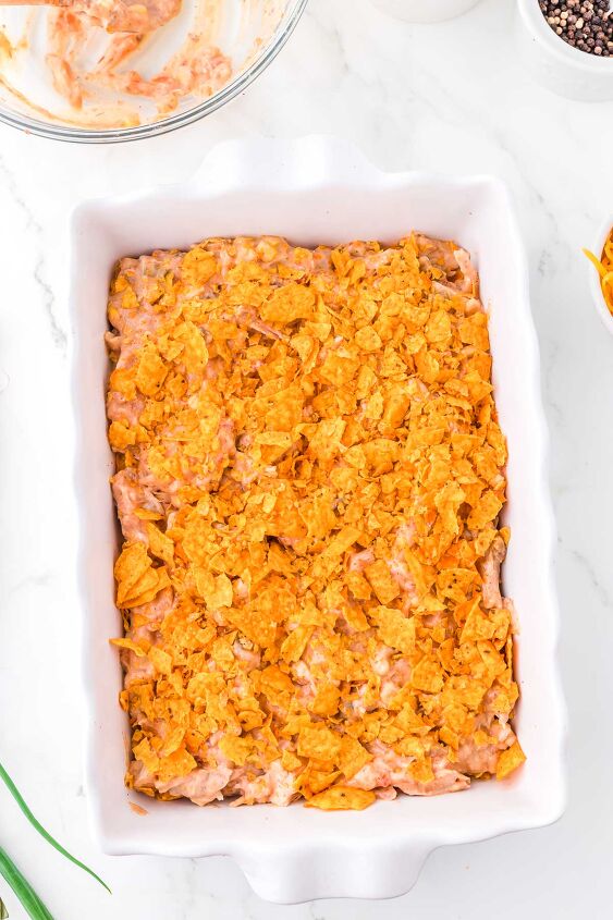 mexican chicken casserole with doritos, Mexican Chicken Casserole with Doritos being layered in a white casserole dish