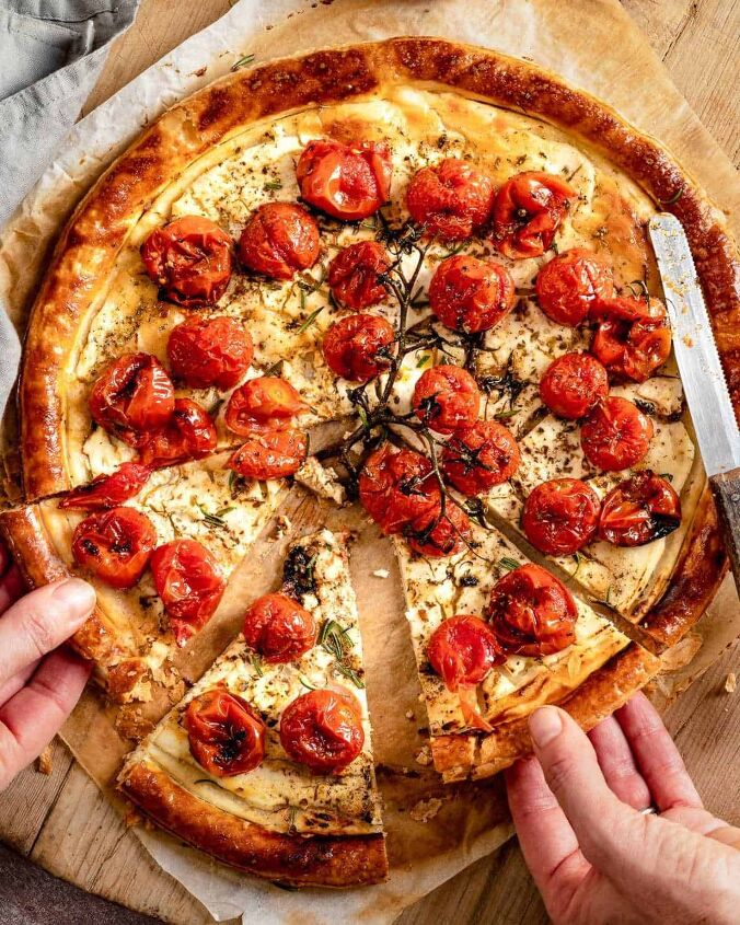 roasted cherry tomatoes tart with cheese, Two hands taking a slice of tomatoes tart